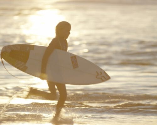 young-surfer-running-through-the-ocean-at-snapper